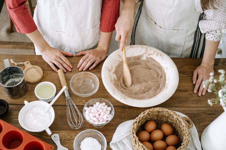 Close-up of homemade baking process with various ingredients and utensils on a wooden table.