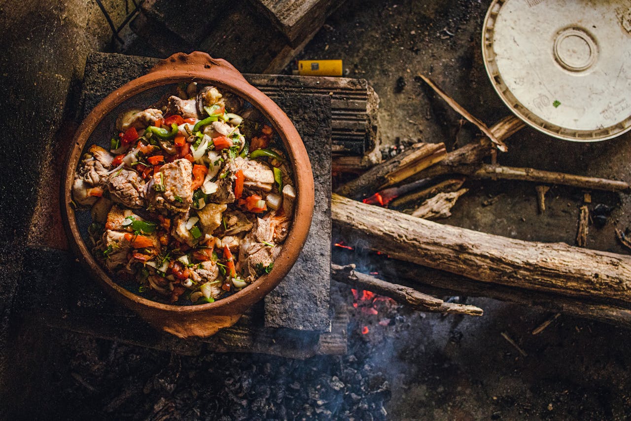 A rustic clay pot cooking meat and vegetables over an open wood fire in Brazil, showcasing traditional cuisine.
